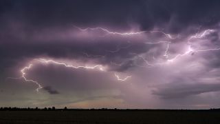 Blitze eines Gewitters erhellen die dunklen Wolken über der Landschaft. (Quelle: dpa/Patrick Pleul)