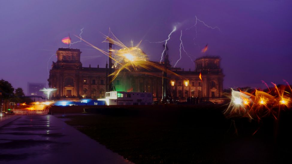 15.08.2023, Berlin: Gewitterblitze sind am frühen Morgen hinter dem Reichstagsgebäude zu sehen. (Quelle: dpa/Paul Zinken)