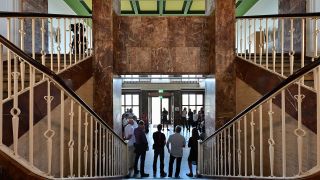 Menschen stehen in der teilweise mit Marmor verkleideten Eingangshalle des ehemaligen Generalshotels am Flughafen BER. Quelle: dpa/Patrick Pleul)