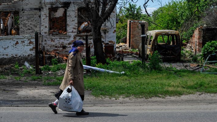 Ein Frau trägt humanitäre Hilfe im Andriivka Dorf in der Nähe von Kiew. (Quelle: imago images/Sergei Chuzavkov)