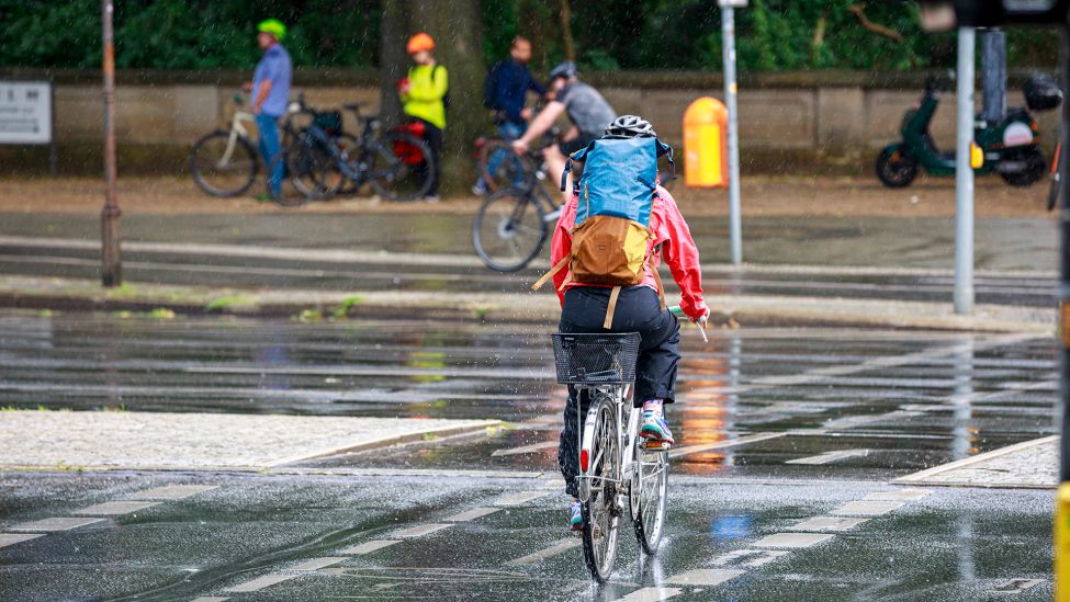 Fahrradfahrerin am 05.07.2023 mitten im Sommerregen auf einer Hauptstrasse. (Quelle: Imago Images/Achille Abboud)