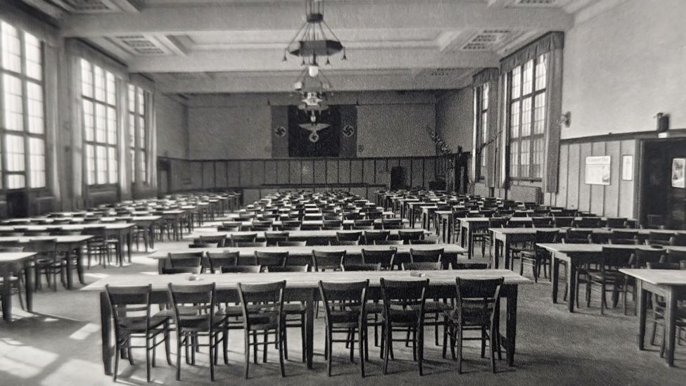 Die Kantine des Arbeiterwohlfahrtsgebäudes der Akkumulatorenfabrik (AFA) in Berlin-Oberschöneweide 1938, im Hintergrund hängen Hakenkreuzfahnen des Nazi-Regimes (Quelle: Presse / CC BY-NC-SA).