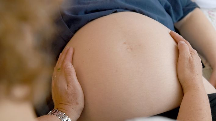 Eine Hebamme tastet am 02.05.2018 den Bauch einer Frau ab, die im neunten Monat schwanger ist. (Quelle: dpa-Bildfunk/Caroline Seidel)