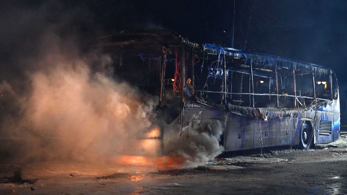 Einsatzkräfte der Feuerwehr löschen am 31.12.2022 an der Sonnenallee im Bezirk Neukölln einen brennenden Bus, der von Unbekannten angezündet worden war. (Quelle: dpa-Bildfunk/Paul Zinken)