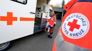 Symbolbild: Eine Rettungssanitäterin steht vor einem Rettungswagen des Deutschen Roten Kreuzes. (Quelle: dpa/Bernd Weißbrod)