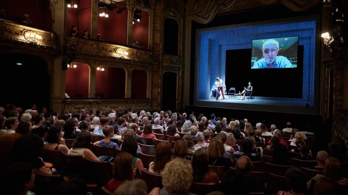 Zum Internationalen Literaturfestival Berlin stellt Schriftsteller Salman Rushdie, live aus New York zugeschaltet, sein Buch «Victory City» vor, während ihn sein Freund und Schriftsteller Daniel Kehlmann von der Bühne aus begrüßt. Auch Übersetzer des Buches Bernhard Robben und Cynthia Micas, Schauspielerin, sitzen im Berliner Ensemble auf der Bühne. (Foto: dpa)