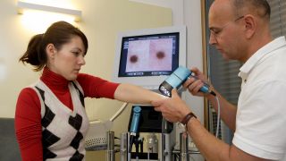 Symbolbild: Dermatologe untersucht Patientin mittels Videodermatoskopie. (Quelle: dpa/O. Ring)
