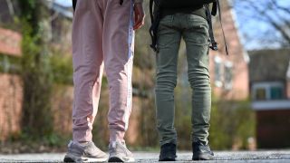 Symbolbild: Eine Schülerin (l) trägt eine Jogginghose, während sie mit einer Mitschülerin, die eine Jeans trägt, auf dem Schulhof einer Schule steht. (Quelle: dpa/L. Penning)