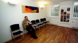 Symbolbild: Mann sitzt Zeitschrift lesend in Wartezimmer für Untersuchung bei Arzt für Innere Medizin. (Quelle: dpa/K. Rose)