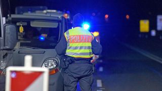 Ein Polizeibeamter steht bei einer Grenzkontrolle neben einem Fahrzeug. (Quelle: imago-images/lausitznews.de)