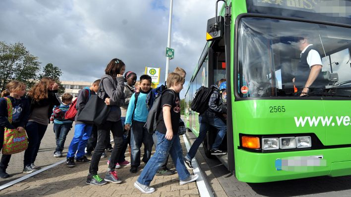 Symbolbild: Kinder steigen in einen Schulbus ein. (Quelle: imago images/Beuning)