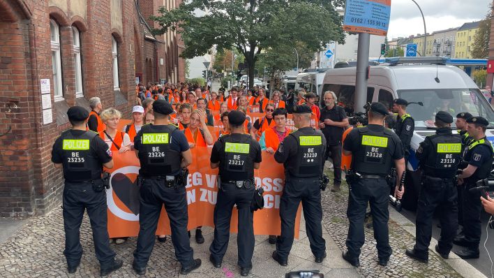 Demonstrierende der Letzten Generation stehen bei der Reformationskirche Moabit vor einer Reihe von Polizist:innen. (Quelle: rbb/M. Bartsch)