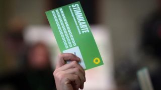 Ein Abgeordneter von Bündnis 90/Die Grünen Brandenburg hält seine Stimmkarte nach oben