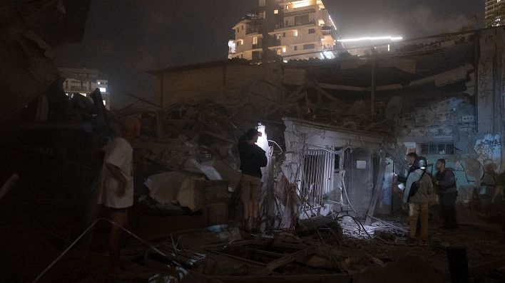Symbolbild: Menschen betrachten am 07.10.2023 die Schäden einer aus dem Gazastreifen abgefeuerten Rakete in Tel Aviv. (Quelle: dpa/AP/Moti Milrod)