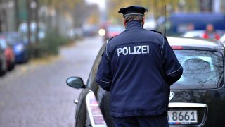 Symbolbild:Ein Polizist schreibt in Berlin einen Strafzettel vor einem falsch geparkten Auto.(Quelle:dpa/Paul Zinken)