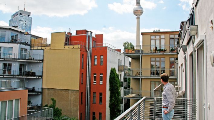 Symbolbild:Ein Mann steht auf dem Balkon seiner Eigentumswohnung in Berlin-Mitte und schaut zum Fernsehturm.(Quelle:dpa/L.Ferstl)