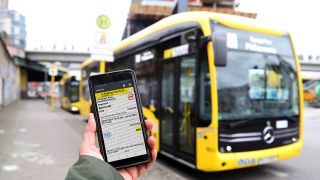 Symbolbild:Eine Hand zeigt ein Handy mit einem digitalen Ticket vor einem BVG-Bus.(Quelle:imago images/S.Gudath)