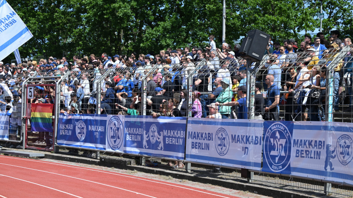 Fans des jüdischen Sportvereins TuS Makkabi stehen auf den Tribünen eines Fußballstadions. (Quelle: IMAGO / Matthias Koch)