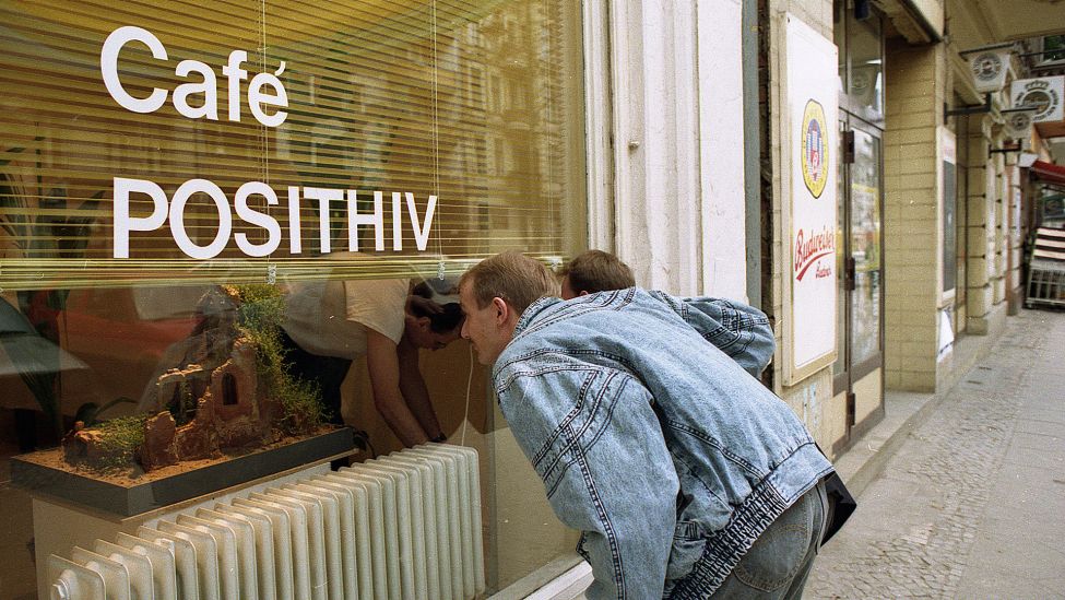 Menschen schauen am 18.01.1990 ins Schaufenster von Berlins erstes AIDS Café das Café Posithiv in der Großgörschenstraße in Schöneberg. (Quelle: Picture Alliance/AP/Roland Weihrauch)