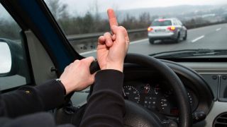 Symbolbild: Autofahrer ärgert sich über einen Raser auf der Autobahn und zeigt seinen Mittelfinger. (Quelle: dpa/Conradi)