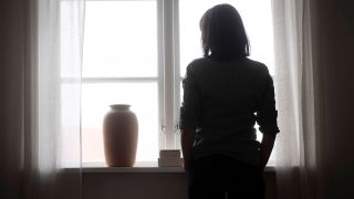 Symbolbild: Eine traurige Frau am Fenster. (Quelle: dpa)