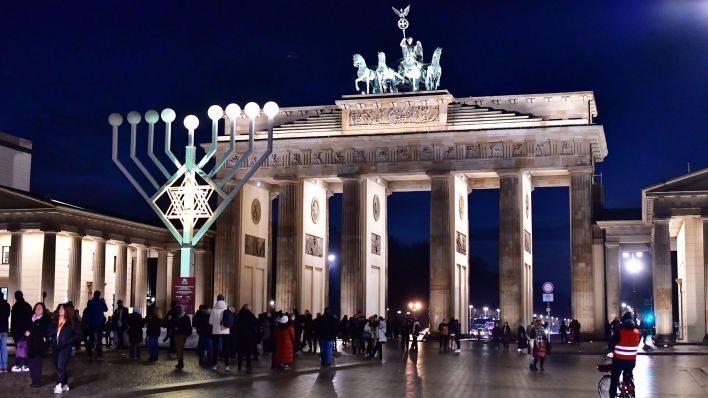 Archivbild: Das illuminierte Brandenburger Tor mit einer stilisierten, siebenarmigen jüdischen Kerzenleuchter-Installation aus Anlass des derzeitigen Chanukka-Festes, am 21.12.2022. (Quelle: dpa/Matthias Tödt)