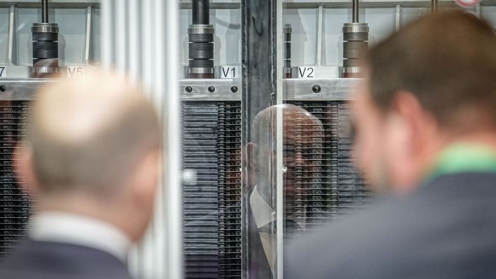 Bundeskanzler Olaf Scholz (SPD) spiegelt sich bei der Eröffnung der Elektrolyseur-Fertigung von Siemens Energy in einem Elektrolyseurstapel (Quelle: dpa)