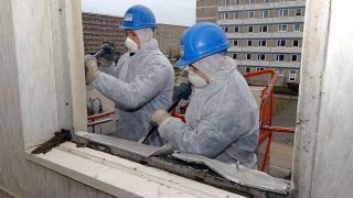 Spezialisten für Asbestsanierung einer Abrissfirma arbeiten beim Abriss eines Plattenbaus (Quelle: dpa/Peter Förster)