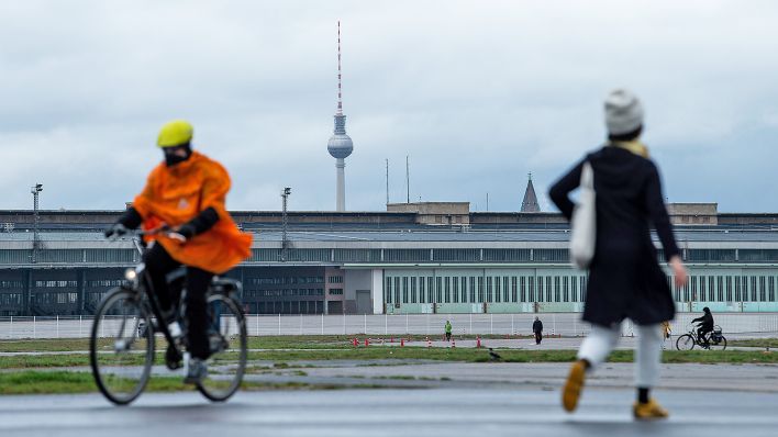 Auf dem Tempelhofer Flugfeld fährt am 19.11.2020 ein Fahrradfahrer und läuft eine Frau. Im Hintergrund der Berliner Fernsehturm. (Quelle: dpa-Zentralbild/Kira Hofmann)