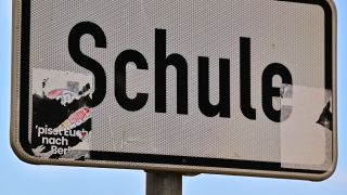 Symbolbild: Ein teilweise entfernter rechtsradikaler Aufkleber ist an einem Schild «Schule» zu sehen. (Quelle: dpa/Patrick Pleul)