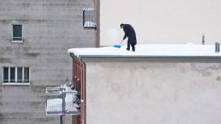Ein Mann räumt am 28.12.2020 Schnee von einem Dach in Berlin. (Quelle: Picture Alliance/Caro/Teich)