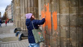 16.11.2023, Berlin: Eine Klimaaktivistin bemalt das Brandenburger Tor mit oranger Farbe. (Quelle: dpa/Annette Riedl)