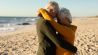 Ein Paar steht am Strand und umarmt sich (Quelle: dpa/Zoonar/Channel Partners)