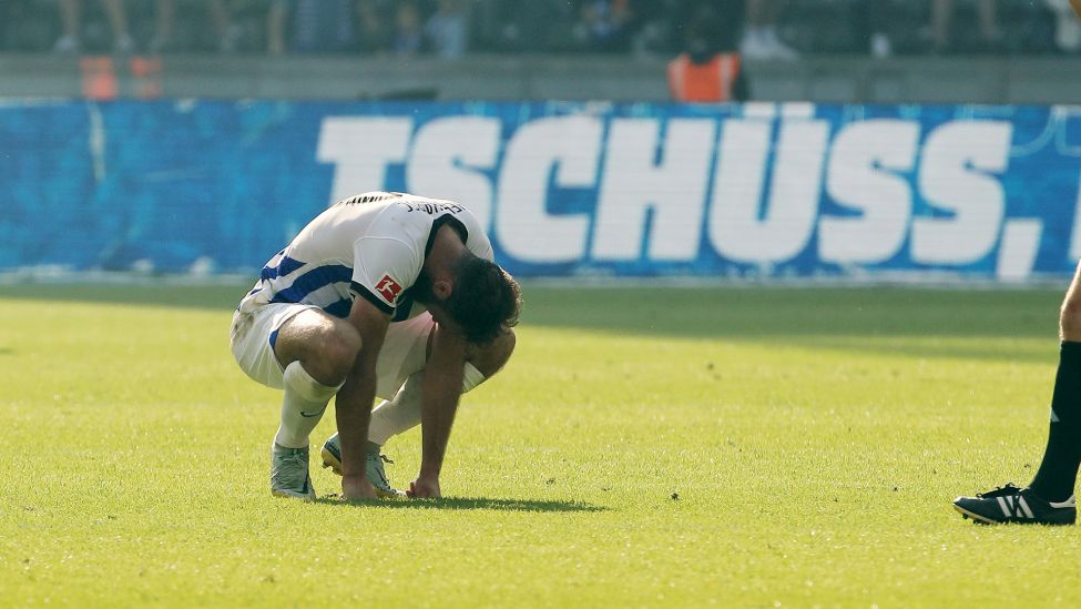 Enttäuscht sitzt der Mittelfeldspieler Lucas Tousart nach dem Abstieg seines Klubs Hertha BSC am 33. Spieltag der Saison 2022/23 in Berlin auf dem Spielfeld (Quelle: dpa / O.Behrendt).