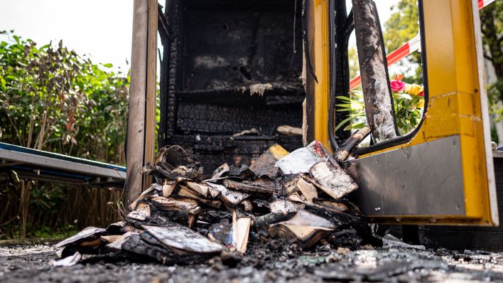 Archivbild:Verbrannte Bücher liegen in der ausgebrannten Bücherbox in der Nähe des Mahnmals "Gleis 17" am 17.08.2023. (Quelle:picture alliance/dpa/F.Sommer)