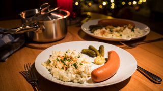 Symbolbild: Das Weihnachtsessen Kartoffelsalat mit Würstchen ist auf einem Teller auf einem Tisch angerichtet.(Quelle:picture alliance/dpa-tmn/C.Klose)