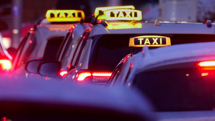 Symbolbild:Die Schilder von freien Taxis leuchten nach Einbruch der Dämmerung an einem Taxistand.(Quelle:picture alliance/dpa/W.Steinberg)