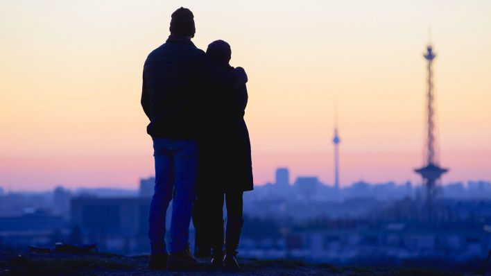 Symbolbild: Ein Liebespaar steht in der Morgendämmerung auf dem Drachenberg vor Berlin mit dem Fernsehturm und dem Funkturm. (Quelle: dpa/Soeder)