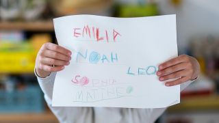Ein Mädchen hat am 08.05.2023 die Vornamen Noah, Emilia, Sophia und Mattheo auf ein Blatt gerschrieben. (Quelle: dpa-Bildfunk/Hendrik Schmidt)