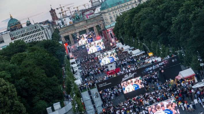 Archivbild: Fans stehen in Berlin auf der Fanmeile vor dem Brandenburger Tor. (Quelle: dpa/Zinken)