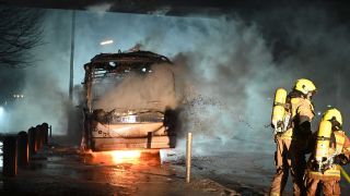 Archivbild: Einsatzkräfte der Feuerwehr löschen in der Silvesternacht an der Sonnenallee im Bezirk Neukölln unter einer Durchfahrt einen brennenden Bus, der von Unbekannten angezündet worden war. (Quelle: dpa/Zinken)