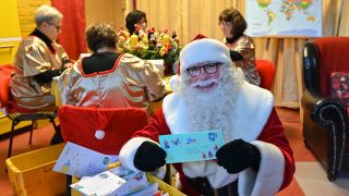 Archivbild: Der Weihnachtsmann sitzt nach der Ankunft im Weihnachtspostamt und zeigt einen von vielen Briefen mit Wunschzetteln. (Quelle: dpa/P. Pleul)