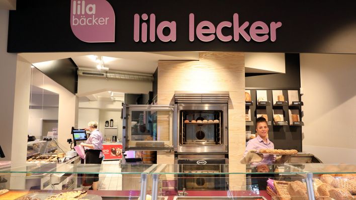 Archivbild: In einer Filiale des Unternehmens Lila Bäcker hält eine Mitarbeiterin ein Blech mit frisch gebackenen Brötchen. (Quelle: dpa/Wüstneck)