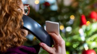 Eine Frau telefoniert vor einem geschmückten Weihnachtsbaum. (Quelle: dpa/Jens Büttner)