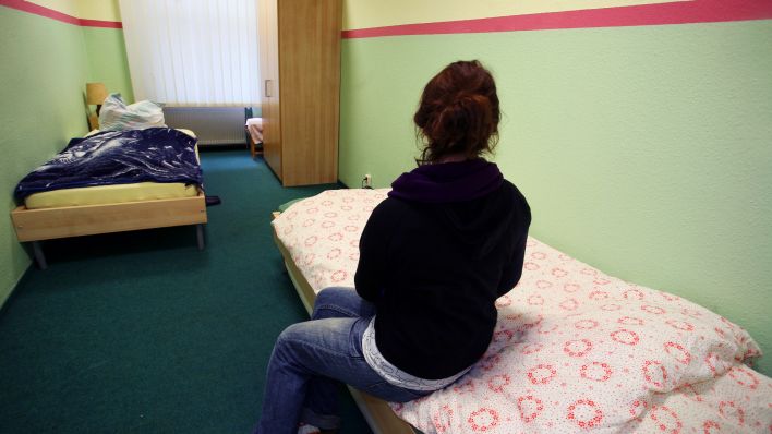 Symbolbild: Eine Frau sitzt in einem Zimmer einer Notunterkunft. (Quelle: dpa/Stephanie Pilick)