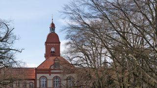 Hinter Bäumen ist das Hauptgebäude der Ruppiner Kliniken im brandenburgischen Neuruppin zu sehen. (Quelle: dpa-Zentralbild/Paul Zinken)