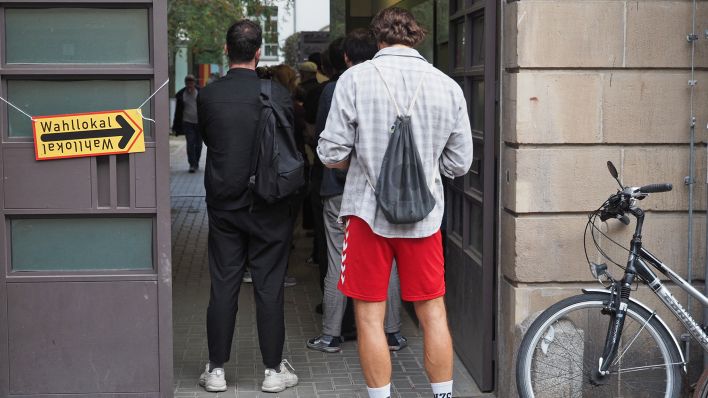 Wahlberechtigte warten deutlich nach 18 Uhr in einer Schlange vor einem Wahllokal an der Mandelstraße im Berliner Stadtteil Prenzlauer Berg darauf, ihre Stimmen zur Bundestagswahl, der Abgeordnetenhauswahl und der Wahl der Bezirksvertretungen abgeben zu dürfen. (Quelle: dpa-Zentralbild/Georg Hilgemann)