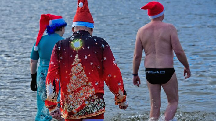 Teilnehmer gehen beim Weihnachts-Eisbaden der Berliner Seehunde im Freibad Orankesee ins Wasser. (Quelle: dpa-Bildfunk/Paul Zinken)