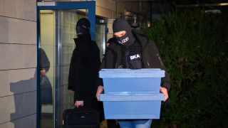 14.12.2023, Berlin: Polizisten gehen mit sichergestellten Beweismitteln aus einem Haus. (Quelle: dpa/Paul Zinken)