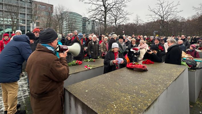 09.12.2023, Berlin: Menschen versammeln sich am Holocaustmahnmal und legen rote Rosen auf die Stelen als Zeichen gegen Antisemitismus.